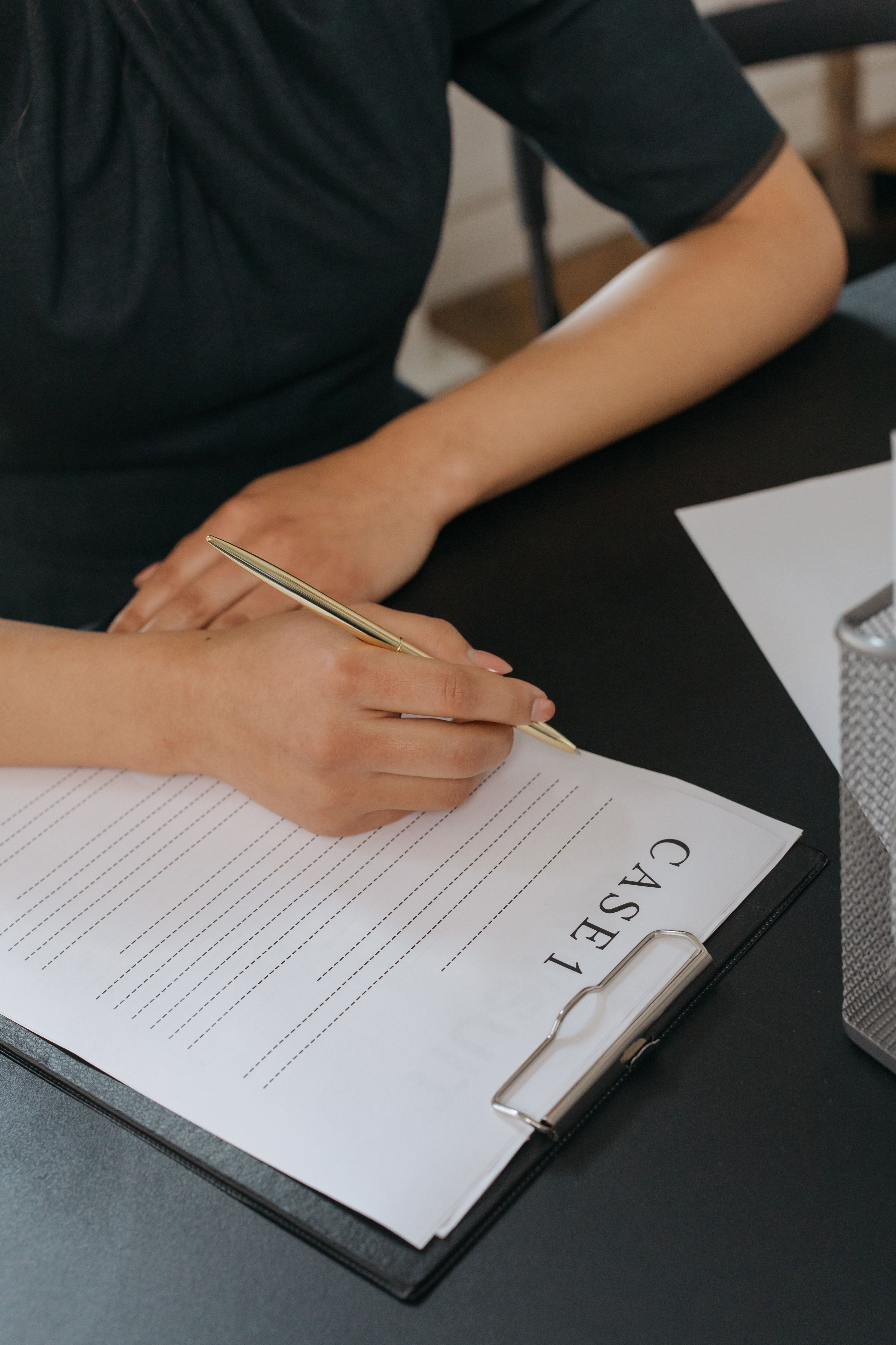 Woman writing on a clipboard labeled Case 1 at a dark desk