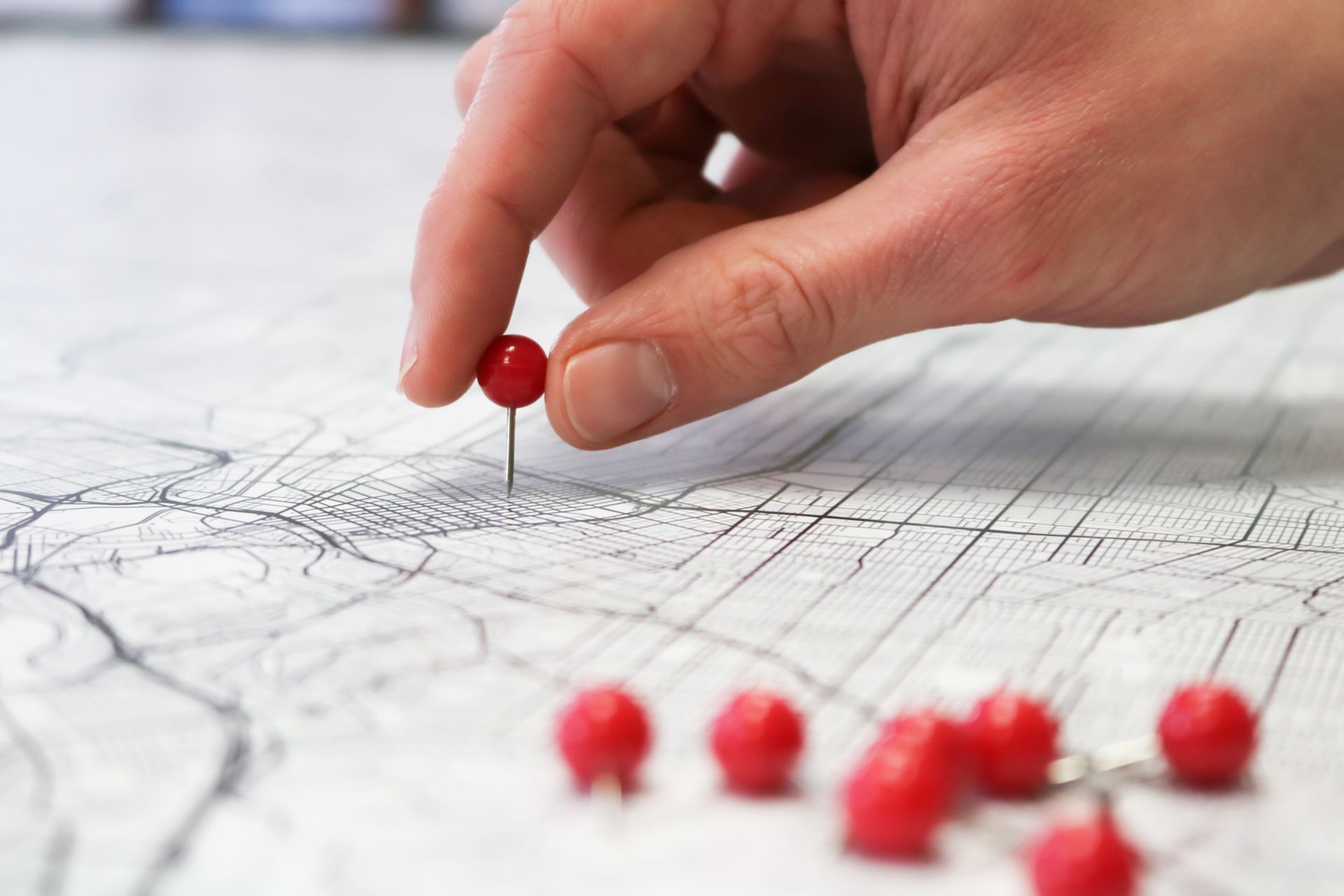 Hand placing a red pin on a paper map