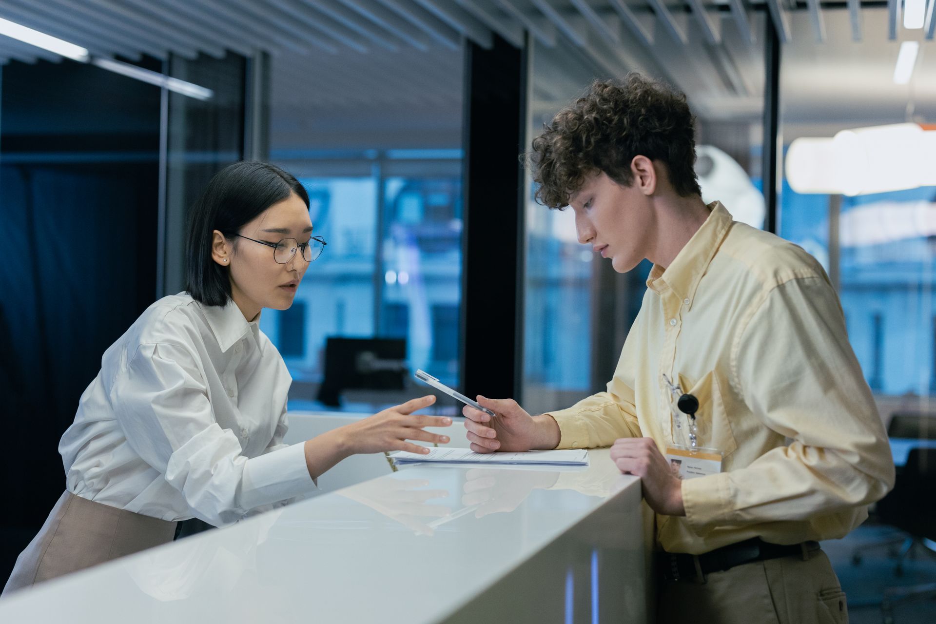 Receptionist helping a client fill out intake paperwork at a desk