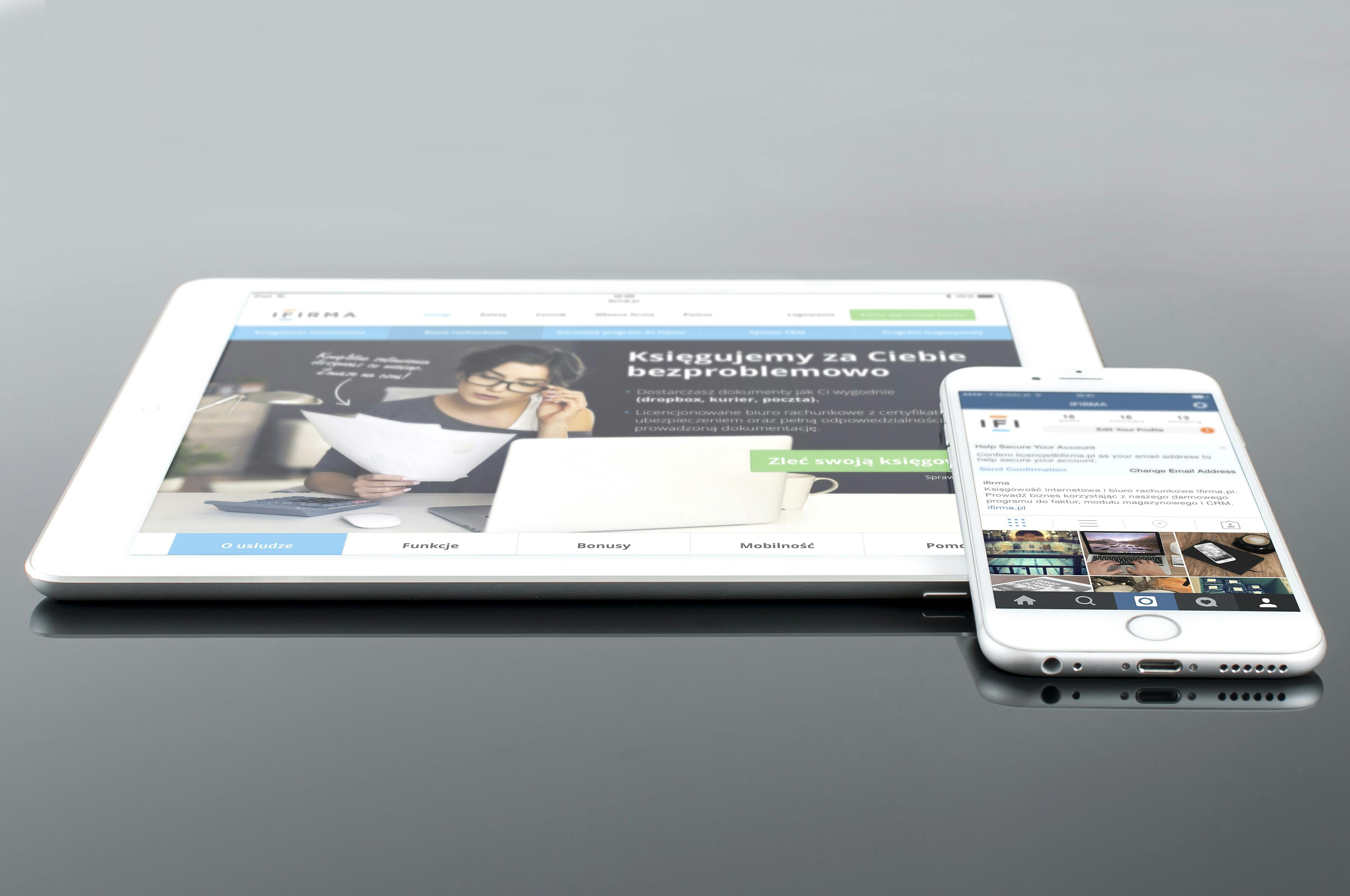 iPad and iPhone side by side on a reflective surface showing a business website and social profile