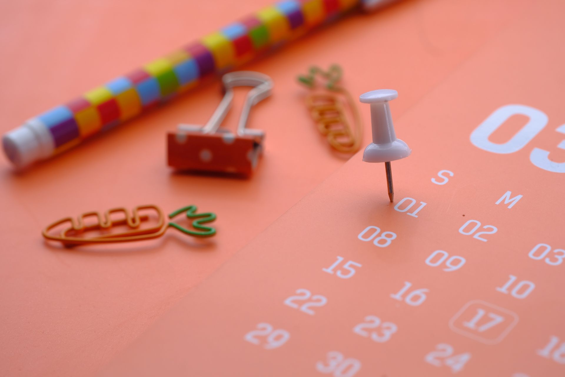 White push pin marking a date on an orange calendar page