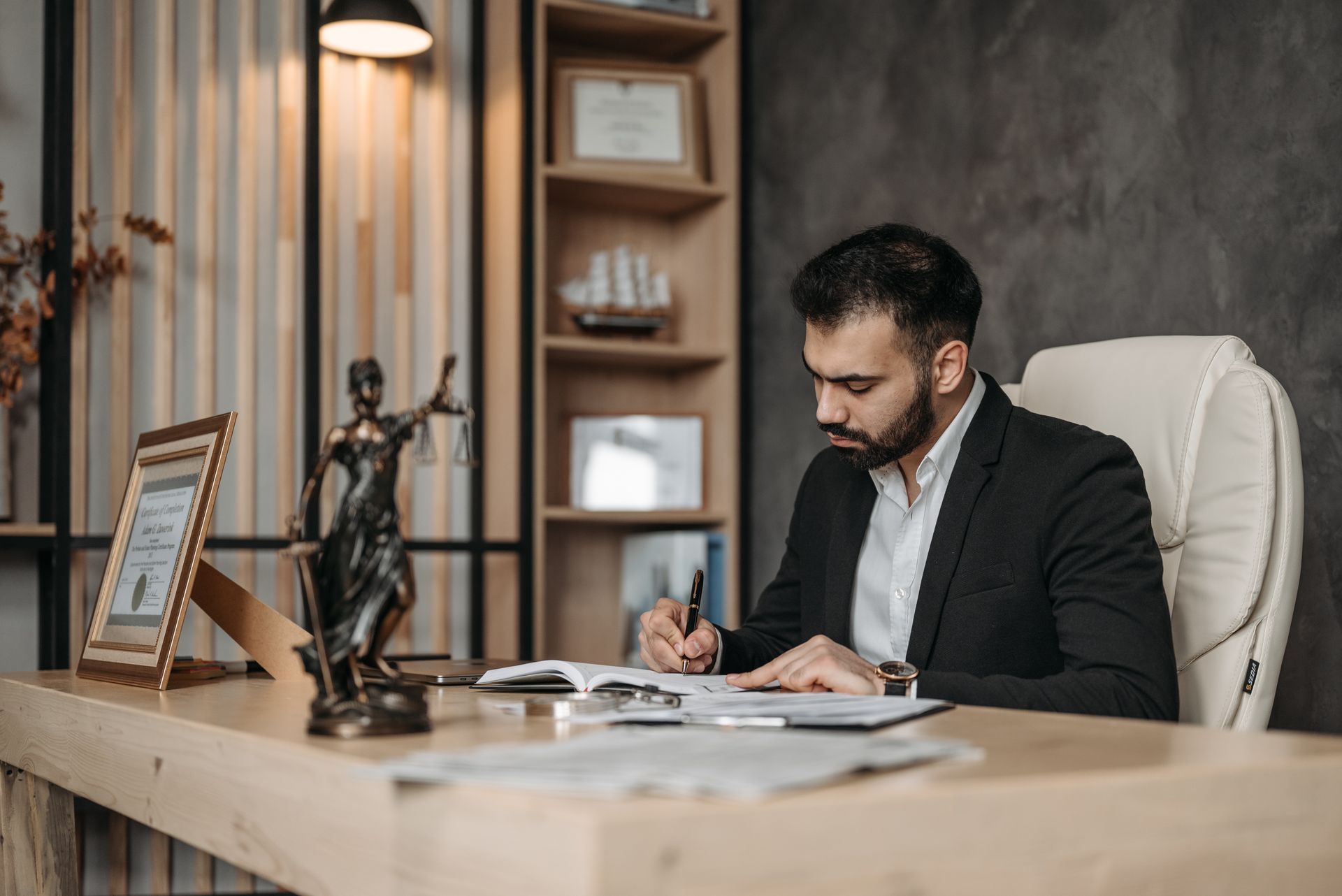 Attorney writing notes in a notebook at an office desk