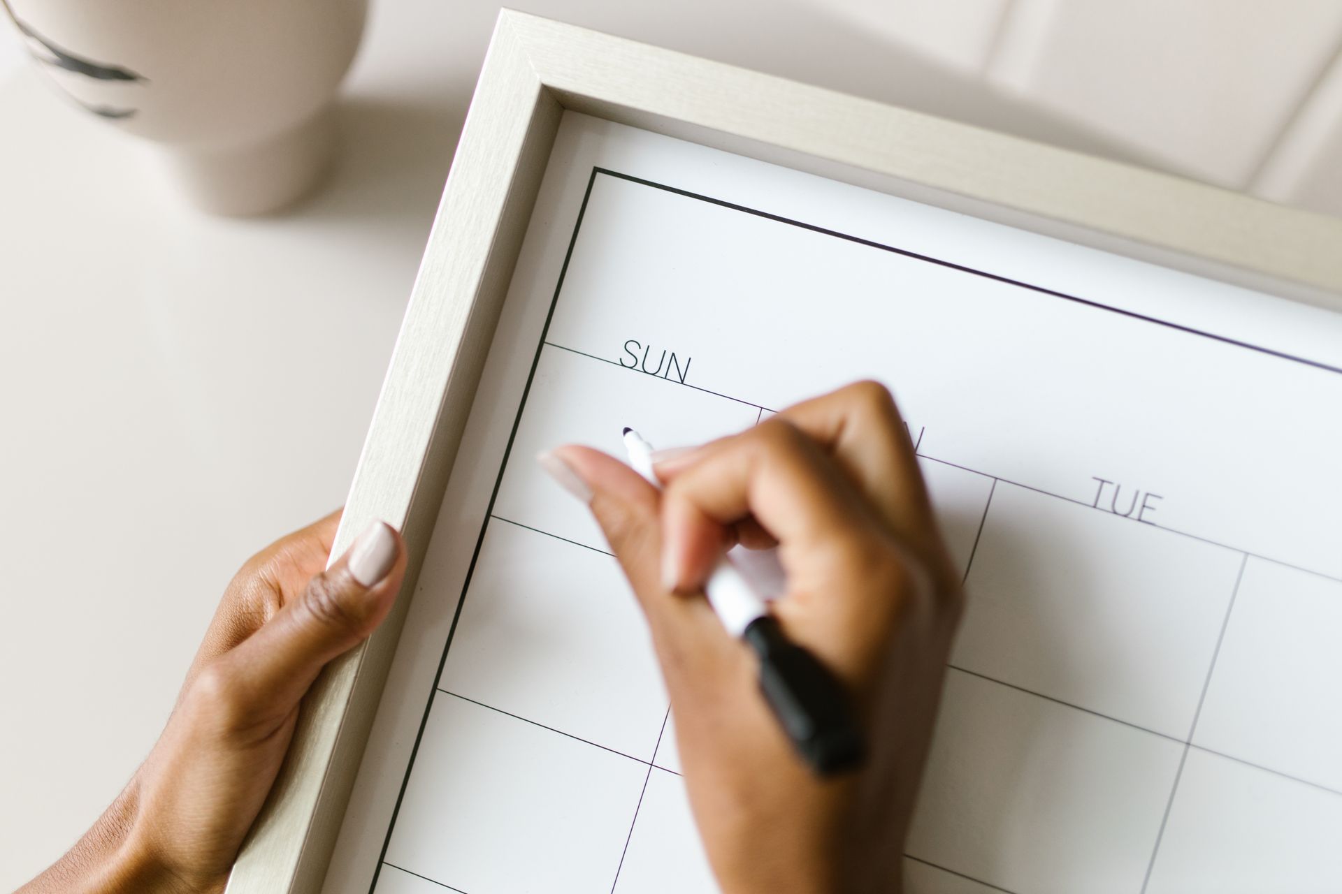 Woman marking dates on a whiteboard monthly calendar