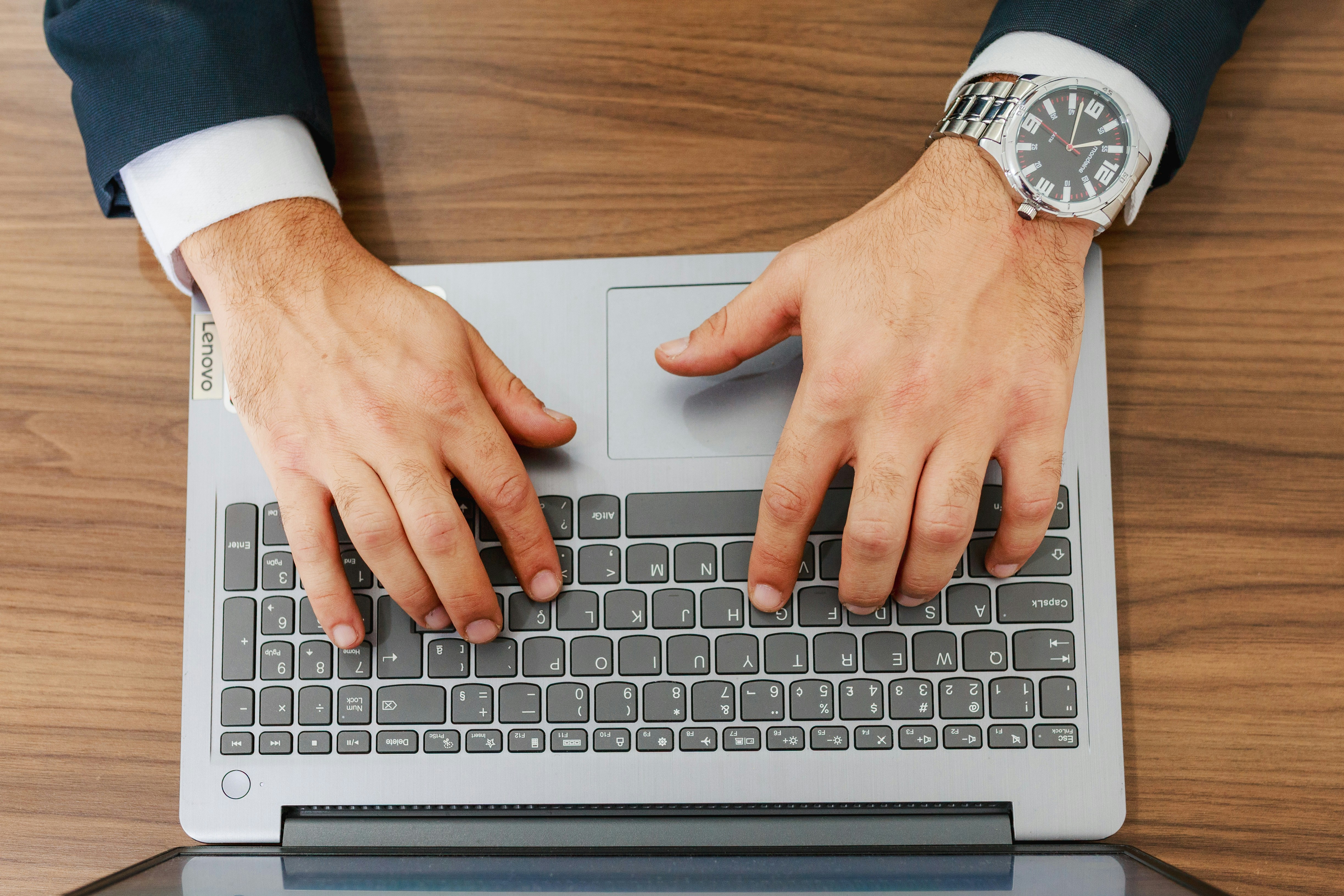 Professional man's hands typing on a laptop at a desk